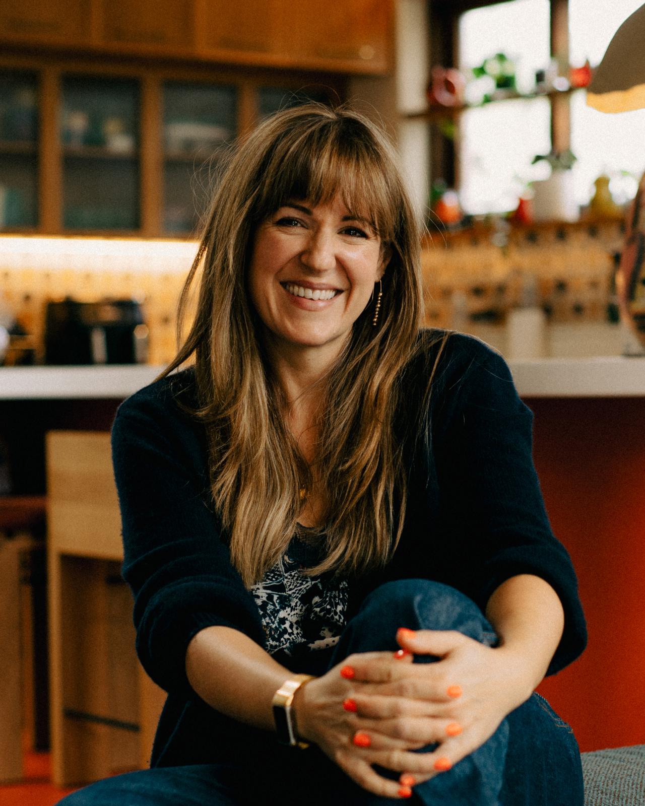 Cyan Ta'eed at home, sitting cross-legged in a sun-lit kitchen, smiling.